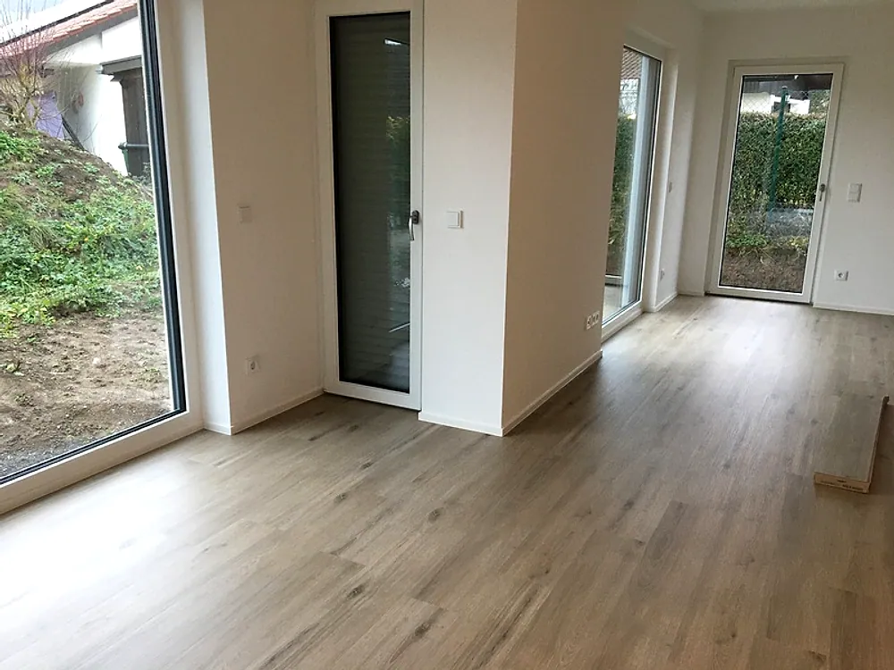 Heller Neubau-Wohnraum mit Eichendiele und Gartentür